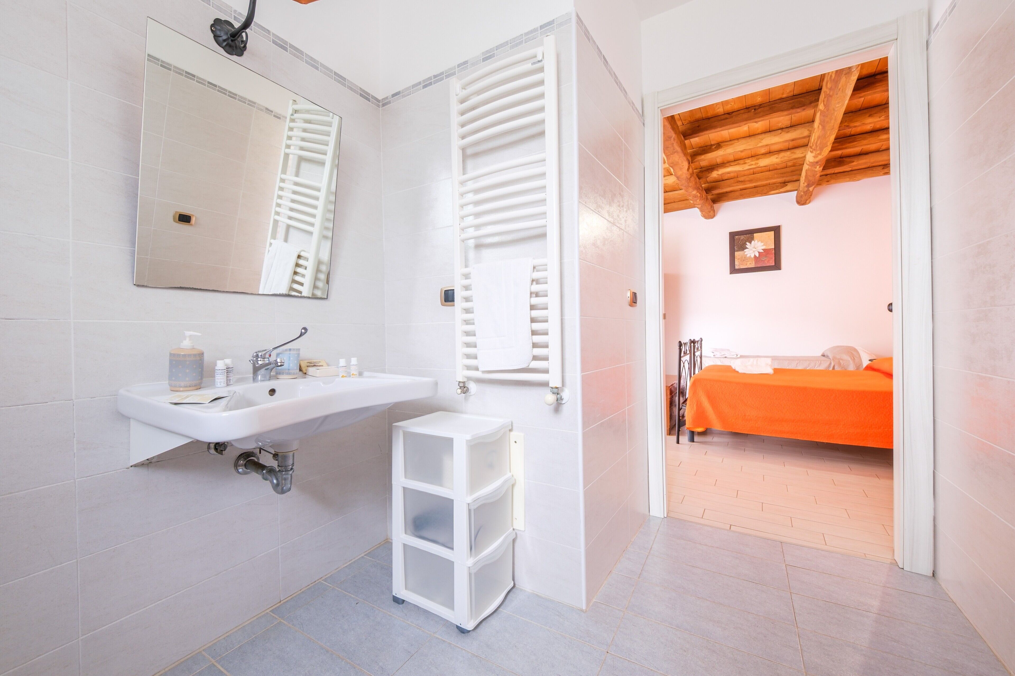 Une salle de bain équipée d’un lavabo, d’un miroir, d’un porte-serviettes et d’un petit meuble de rangement.
