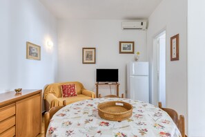 A room with a bed, a television, a refrigerator, and a wooden dresser. - Apartment 'Trande' with Balcony, Wi-Fi and Air Conditioning (Santa Maria di Leuca)