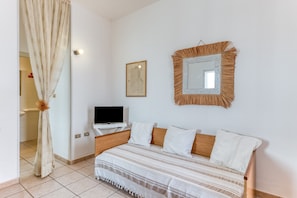 A bedroom with a bed, a television, a framed picture, and a mirror. - Apartment 'Trande' with Balcony, Wi-Fi and Air Conditioning (Santa Maria di Leuca)