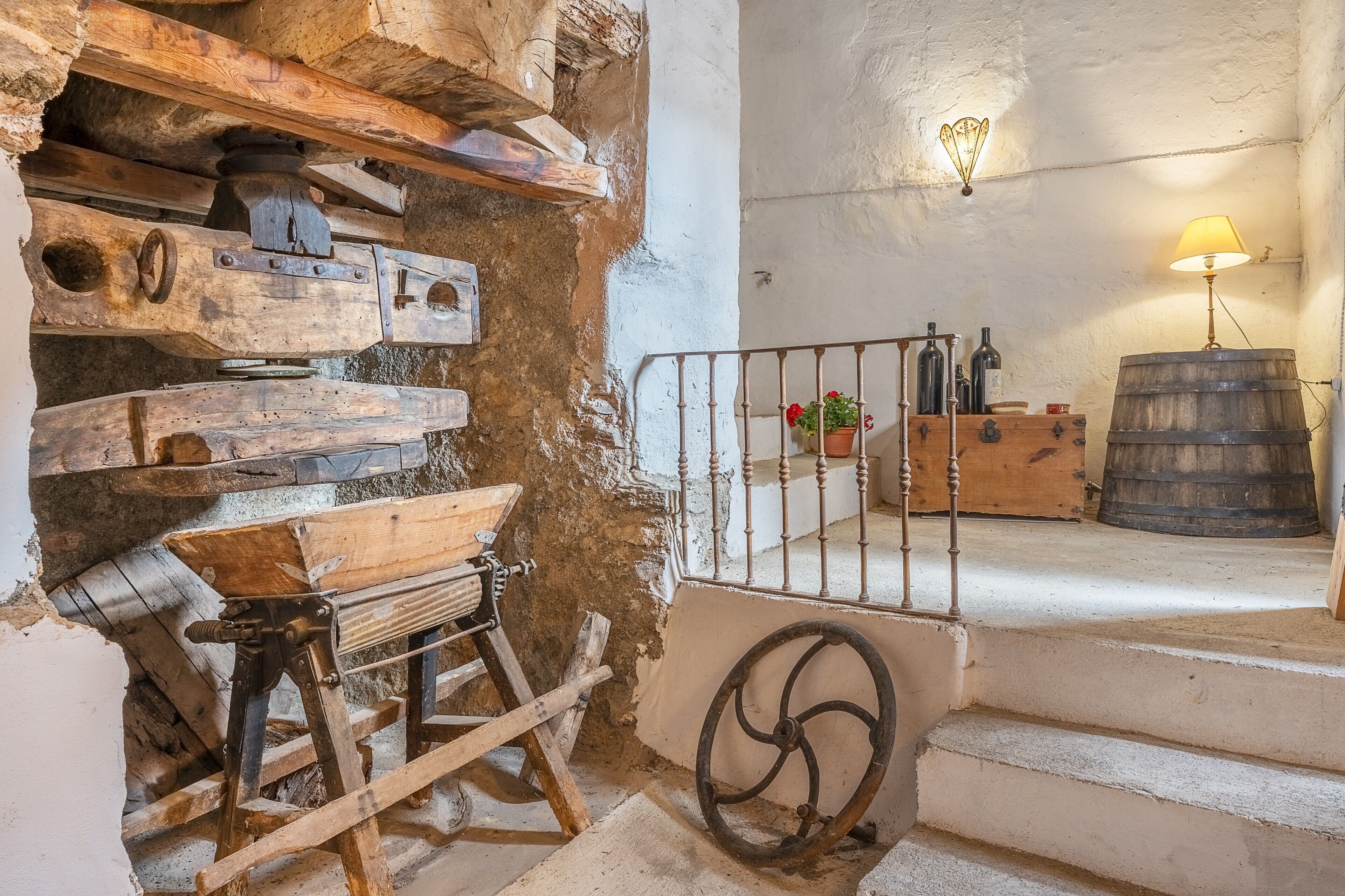 A rustic interior with wooden furniture, a metal railing, and a wooden barrel.