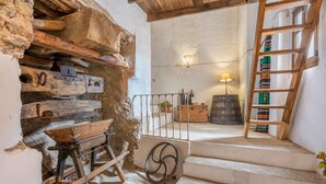 A rustic interior with wooden beams, a wooden bench, a ladder, and a staircase leading to a window. - La Prensa Attic (Sorvilán)