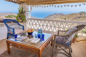 A terrace with wicker chairs, a glass table, and a view of the sea. - La Prensa Attic (Sorvilán)