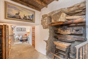 A rustic interior with a wooden ceiling, a painting of deer, and a stone wall with wooden planks. - La Prensa Attic (Sorvilán)