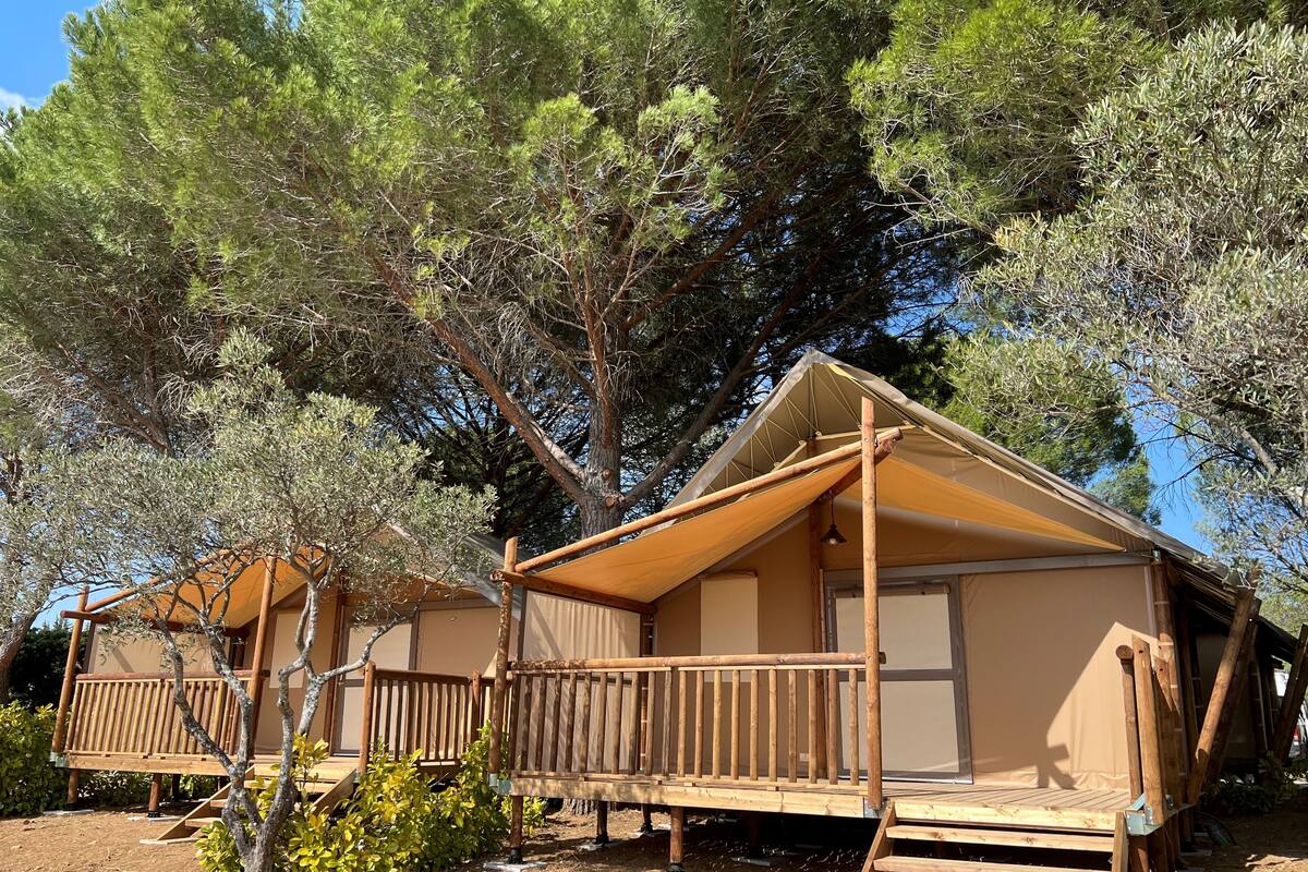 Two wooden cabins with balconies, surrounded by trees.