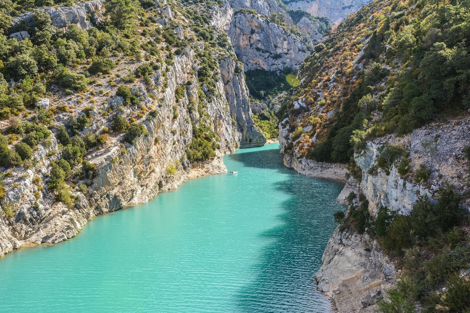 Un cañón con un río turquesa, acantilados rocosos y vegetación escasa.