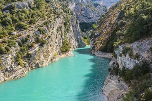 Un cañón con un río turquesa, acantilados rocosos y vegetación escasa.