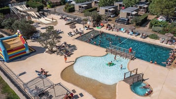 Un área de piscina con tobogán, sillas de descanso y un pequeño puente sobre el agua.