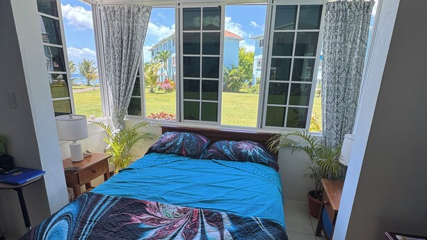 Une chambre avec un grand lit, une fenêtre avec des rideaux, un bureau et une commode.