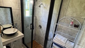Une salle de bain moderne avec une douche à parois de verre, un lavabo avec un miroir et des toilettes dotées d’une étagère au-dessus.