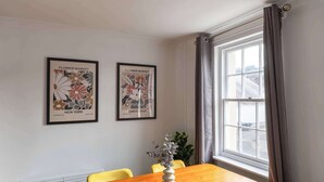 Un comedor con una mesa de madera y sillas amarillas, un sofá gris y dos cuadros en la pared.