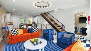 Ein modernes Wohnzimmer mit einer Couch, Sesseln und einem Couchtisch. Eine Treppe führt zu einer weiteren Ebene.