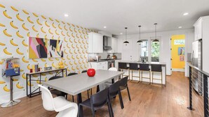 Eine moderne Küche mit Essbereich, mit einer Wand mit Bananenmuster, einer roten Vase und Holzboden.