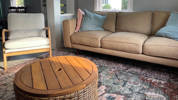 Un salon avec un canapé beige, une chaise en bois et une table ronde en bois.