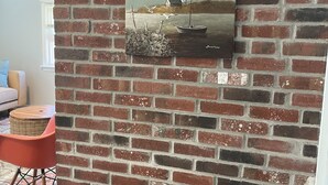 Un mur de briques orné d’une peinture représentant un phare et des mouettes.
