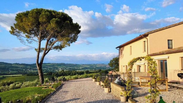 A house with a gravel driveway, outdoor seating, and a view of the countryside.