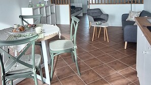 A dining area with a wooden ceiling, tiled floor, and a table set with chairs.