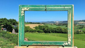 A green-framed picture with a rural landscape view.