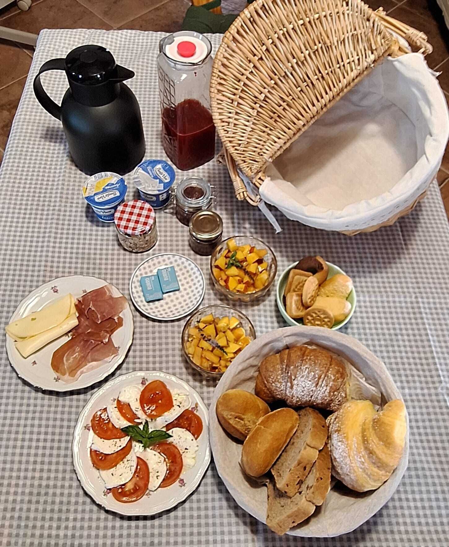 Une table garnie de divers aliments, notamment du fromage, de la charcuterie et des pâtisseries, ainsi que des condiments et une machine à café.