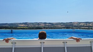 A person relaxing in a swimming pool with a view of rolling hills in the background.