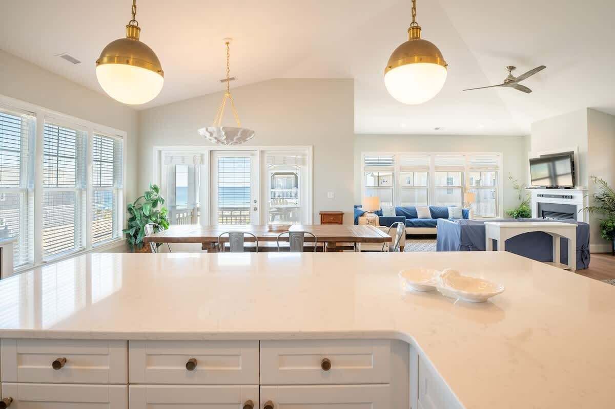 A spacious kitchen with a large island, pendant lights, and a dining area with a table and chairs.