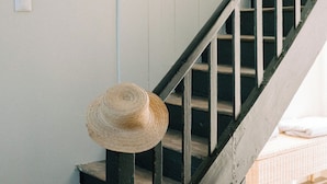 A staircase with a wooden handrail and a straw hat placed on the first step. - Maison Eudoise, swimming pool and spa (Eu)