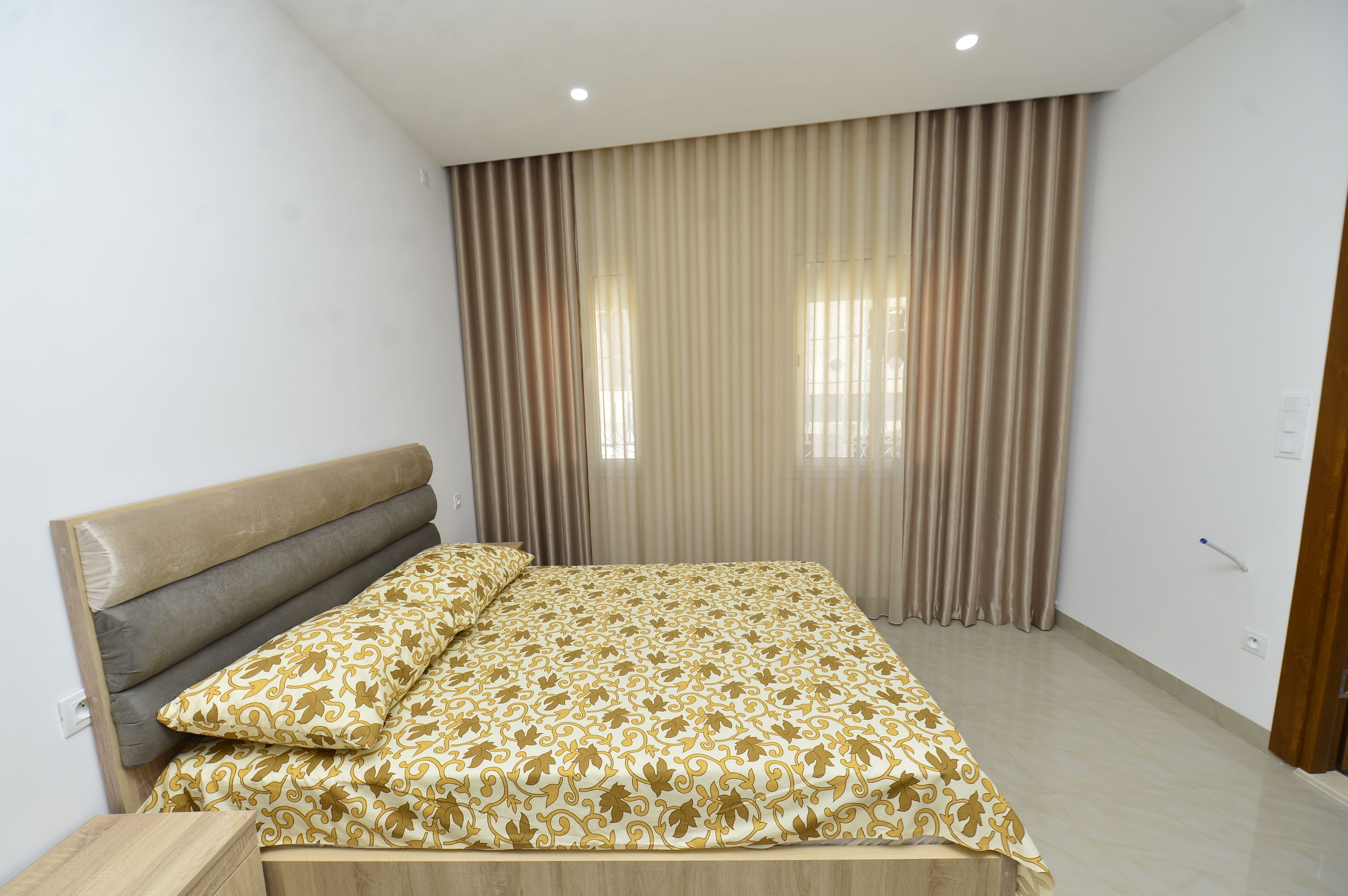 A bedroom with a bed, curtains, and a wooden headboard.