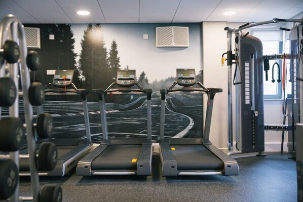 A gym with treadmills, weight machines, and a mural of a winding road. - Student Only Europa House (Portsmouth)