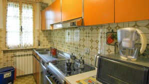 A kitchen with orange cabinets, a stove, a sink, and a microwave.