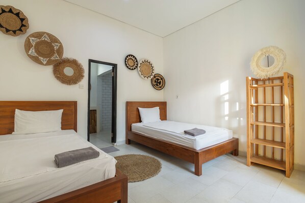 A room with two wooden beds, a woven rug, and wall decorations. - Soleia Surf Camp (Tibubeneng)