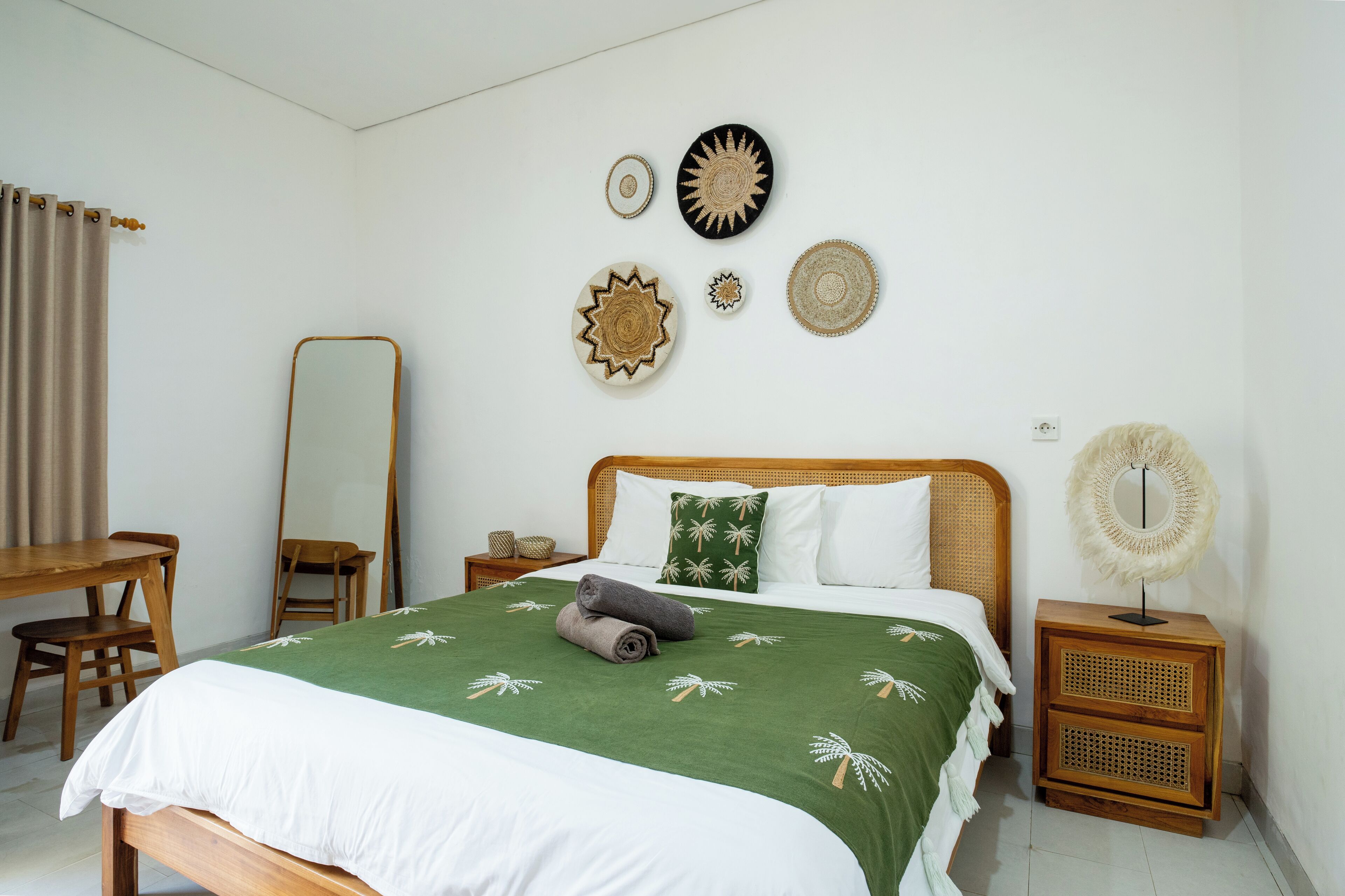 A neatly arranged bedroom with a bed, bedside table, and a mirror.