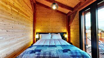Une petite pièce en bois, avec un lit, deux lampes de chevet et une fenêtre.