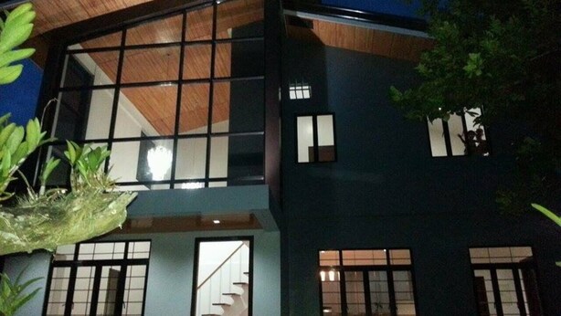 Un edificio moderno de dos pisos, con ventanas grandes y una escalera visible que conduce al nivel superior.
