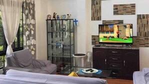 Una sala de estar moderna con una televisión de pantalla plana, un aparador de vidrio y un sofá.