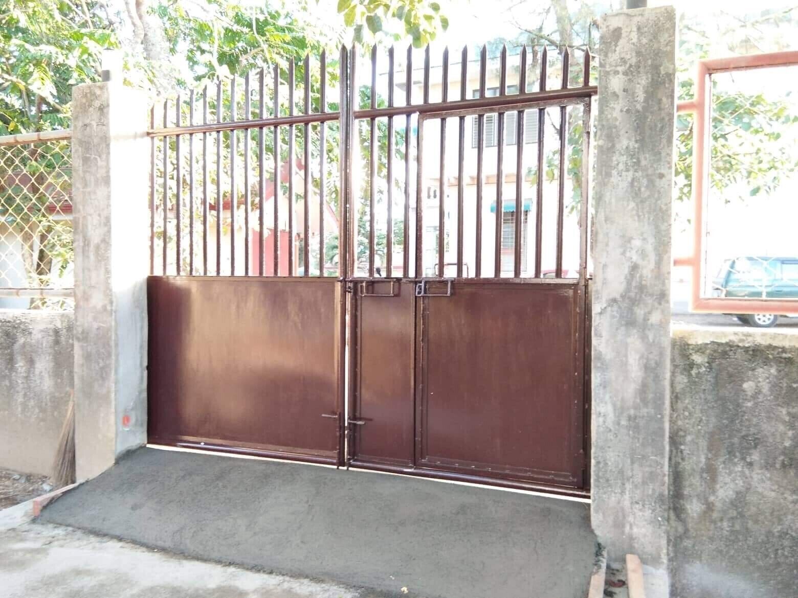 Una entrada protegida con una cerca de metal y una rampa de concreto que lleva a una puerta.