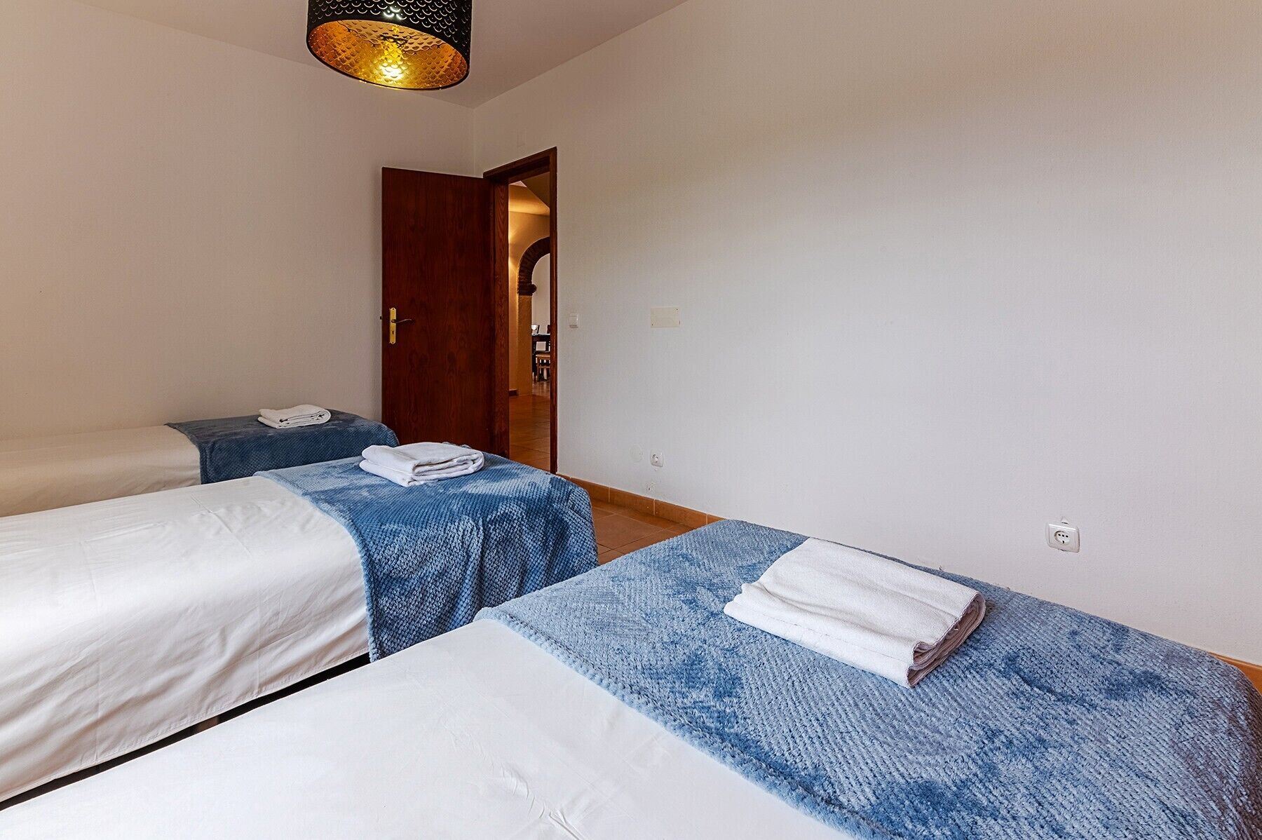 Habitación de hotel con dos camas, una puerta de madera y una lámpara.