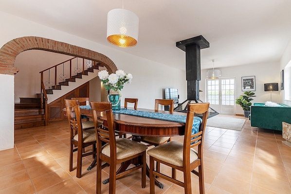 A dining area with a wooden table, chairs, and a vase of flowers.