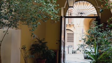 Un arco d'ingresso conduce a un cortile con piante in vaso e un sentiero in pietra.