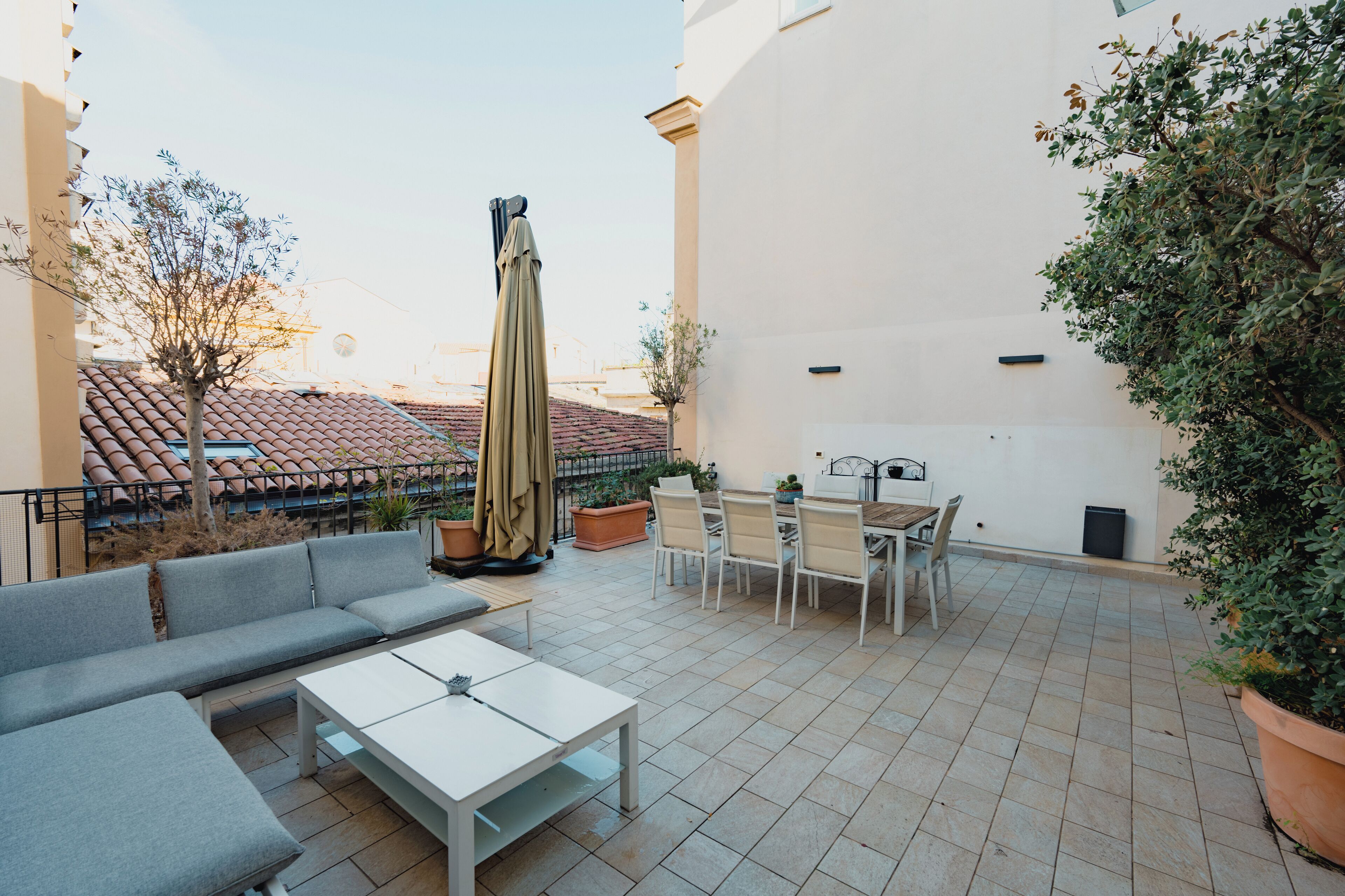 Eine Terrasse im Freien mit einer Couch, einem Tisch, Stühlen und einem großen Sonnenschirm.
