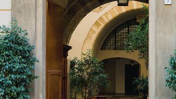 An arched entrance with a wooden door, potted plants, and a stone pathway leading to an interior courtyard.
