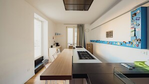 Une cuisine moderne dotée d’un îlot central, d’une cuisinière intégrée et d’une fenêtre laissant entrer la lumière naturelle.