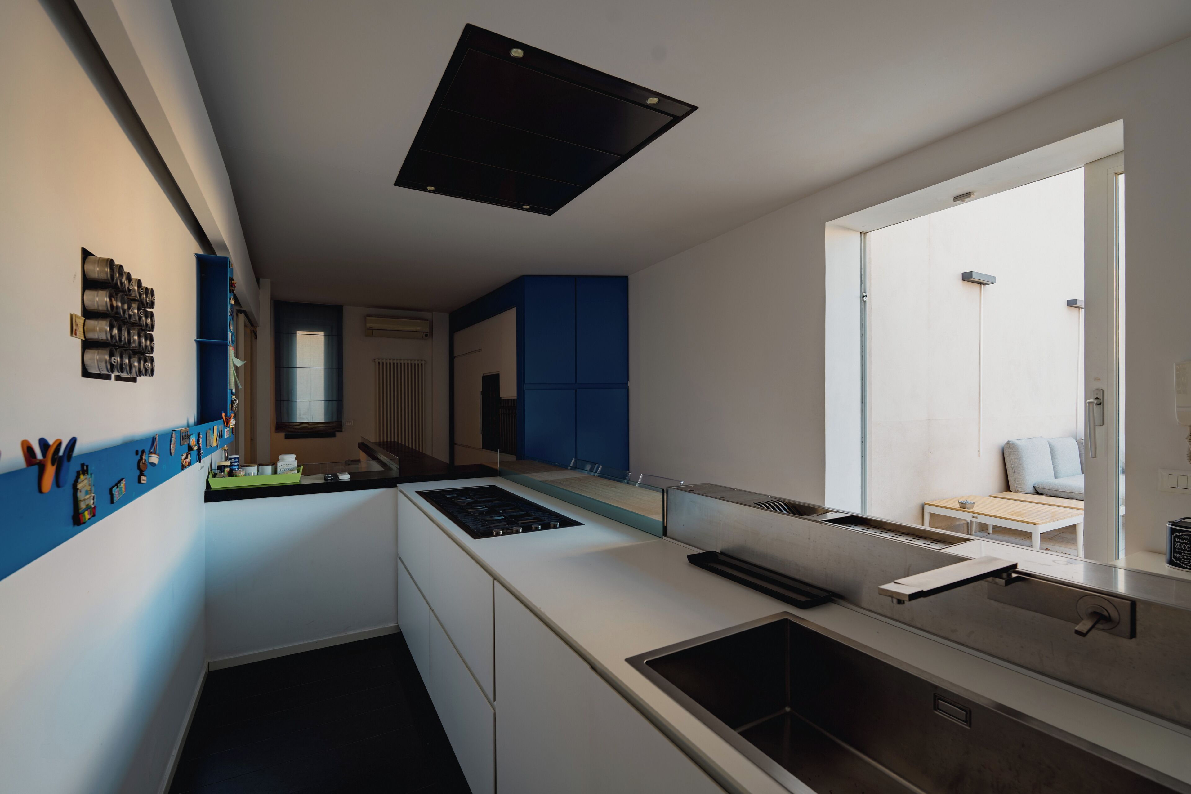 A modern kitchen with a central island, blue cabinets, and a view to a dining area.