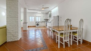 Une cuisine spacieuse avec un coin repas, un lave-linge et un ventilateur de plafond.