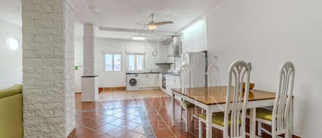 A spacious kitchen with a dining area, a washing machine, and a ceiling fan.