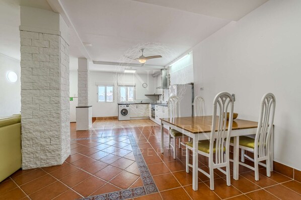 A spacious kitchen with a dining area, a washing machine, and a ceiling fan.