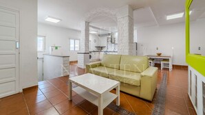 Un grand espace de vie comprenant un canapé, une petite table et une cuisine à l’arrière-plan.