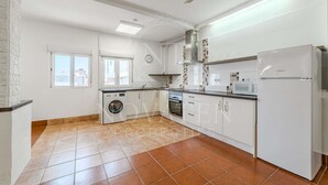 Une cuisine moderne avec des meubles blancs, un four encastré, un four à micro-ondes et un réfrigérateur.
