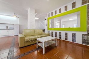 Un salon moderne avec un canapé, une table basse et un grand miroir doté d’un cadre vert.