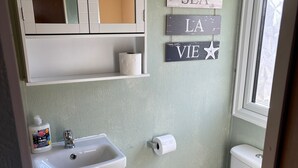 Baño con inodoro, lavamanos, armario y ventana.