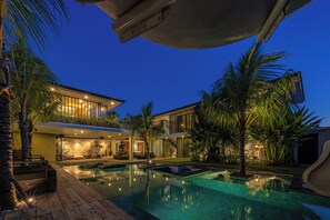 Une maison moderne dotée d’une piscine, d’un espace salon extérieur et de palmiers.