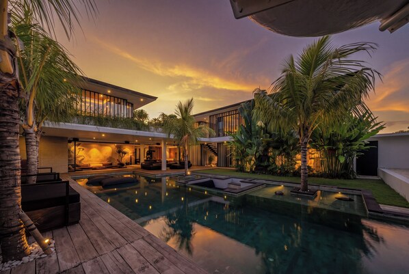 Une maison moderne dotée d’une piscine, d’un espace salon extérieur et d’un patio bien éclairé.